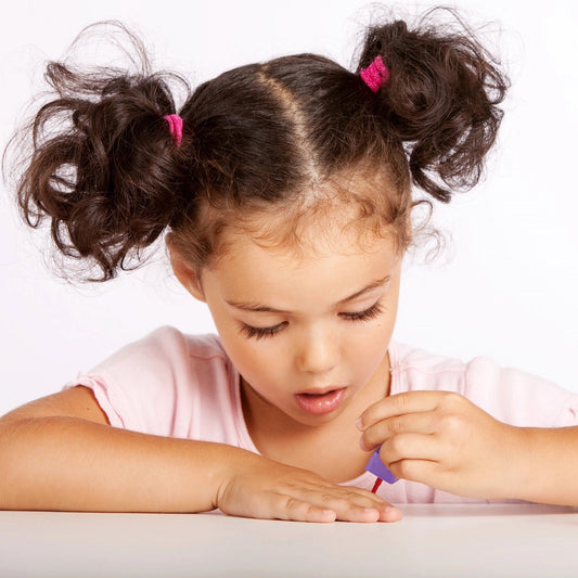 Little Girl applying peel off nail polish herself.