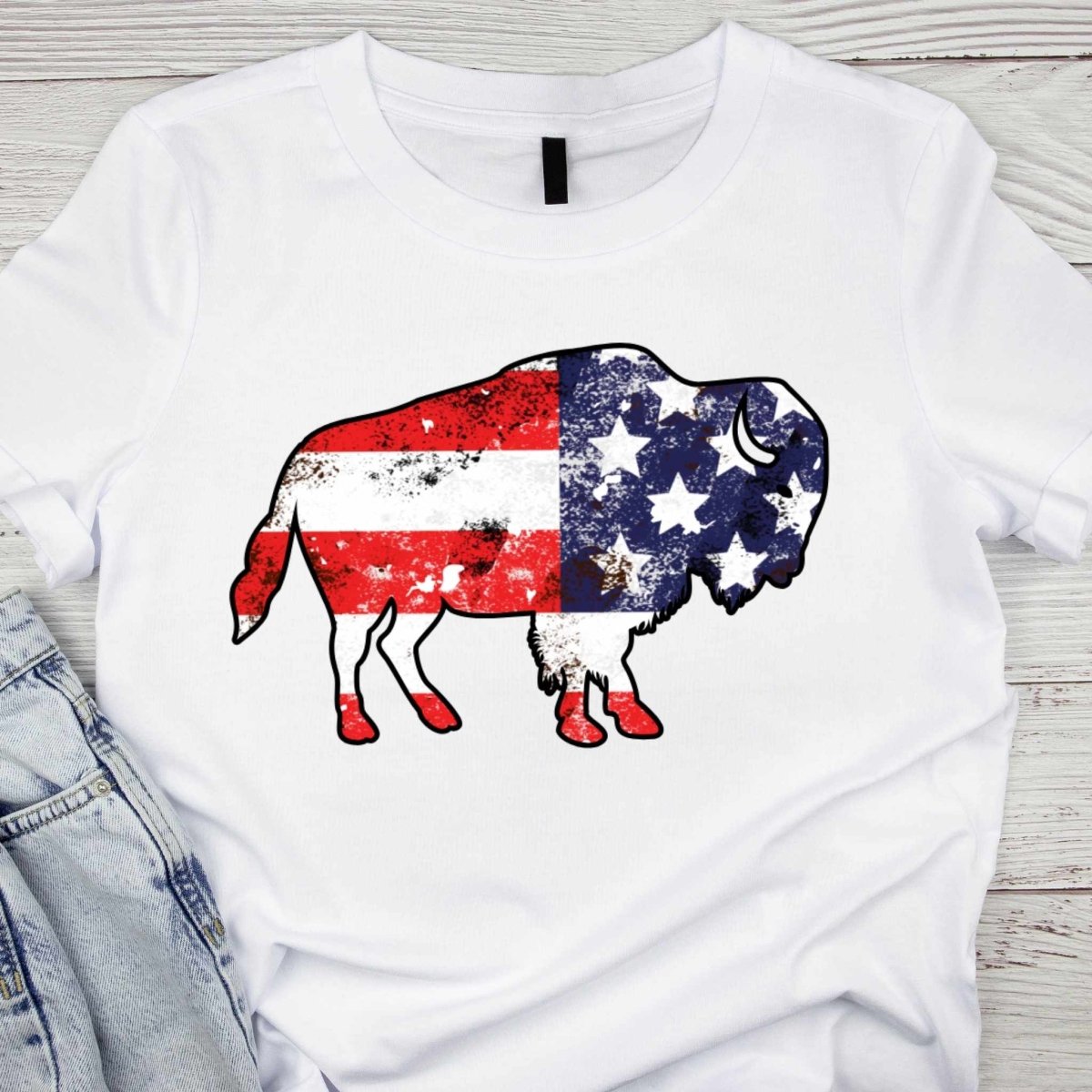Close up White adult unisex tshirt with Buffalo American Flag Graphic on front - shown on light wood background - Little Gift Nook