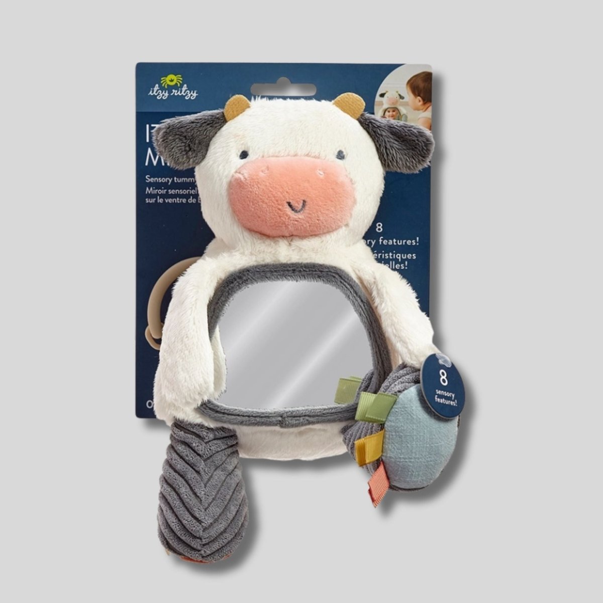 Itzy Ritzy New Itzy Bitzy Mirror Cow Texture Baby Toy. Soft Plush white and gray textured cow with mirror on tummy. Shown on gray background- Little Gift Nook