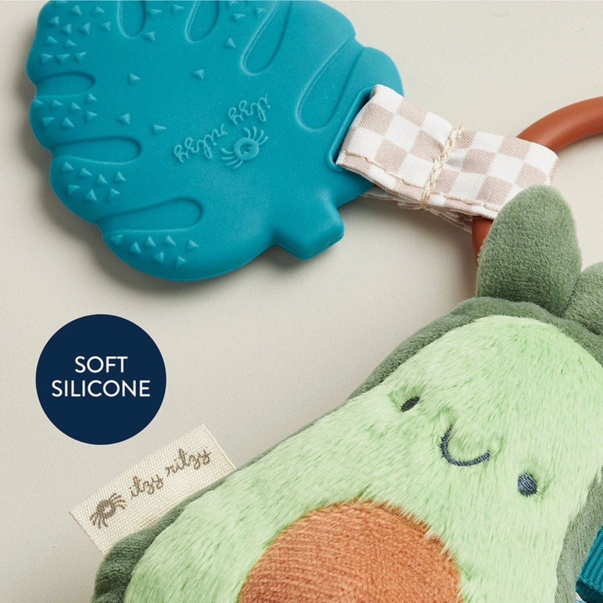 Close up of soft silicone teal leaf teether and plush green avocado baby toy set.