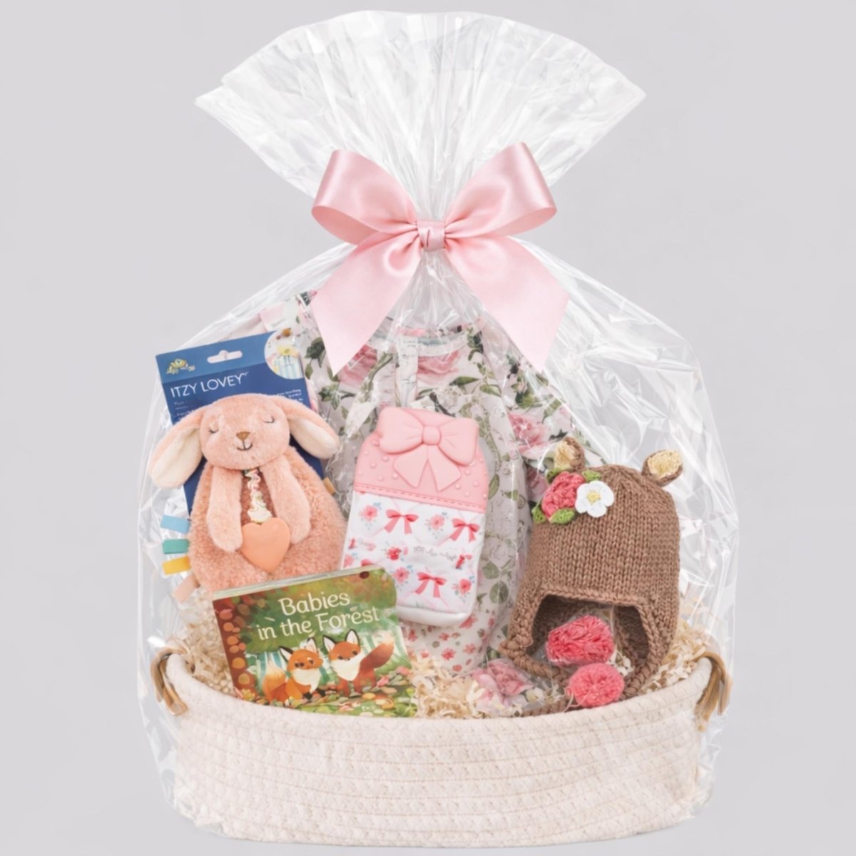 Baby girl gift basket bundle in basket with cellophane and bow on a gray background. Little Gift Nook