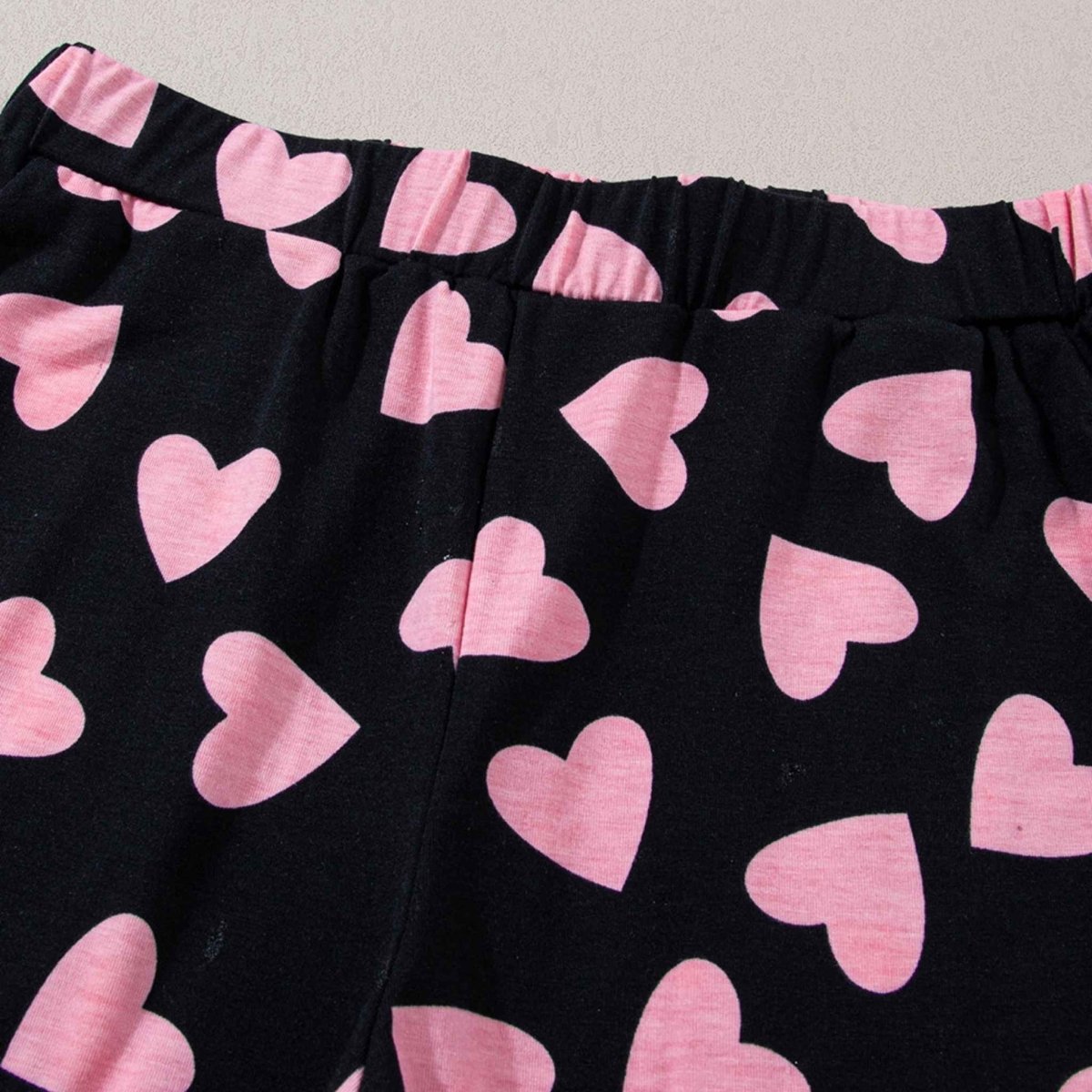 Black Pink Heart Shorts Pajamas set. Black long sleeve top with cuffs and pink heart print all over. Close up of elastic waist on shorts. Black soft shorts, elastic waist, same heart print. Little Gift Nook.