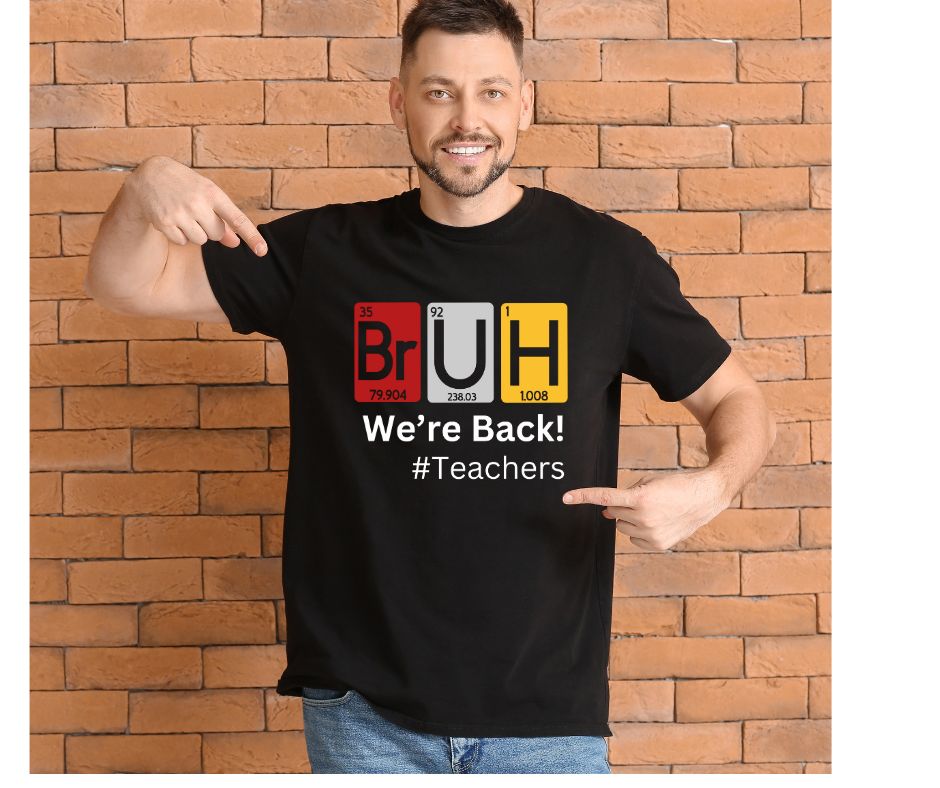 Man wearing a black t-shirt with 'BRUH We're Back! Periodic table elements #Teachers' text against a brick wall.