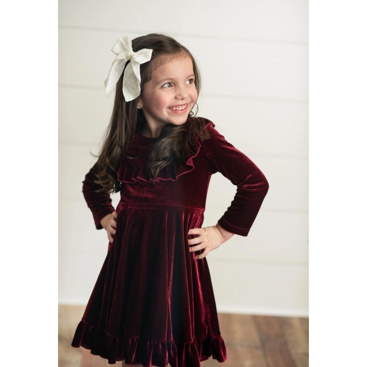 Burgundy Velvet Twirl Holiday Dress. Little Girl modeling dress with hair bow. Little Gift Nook.