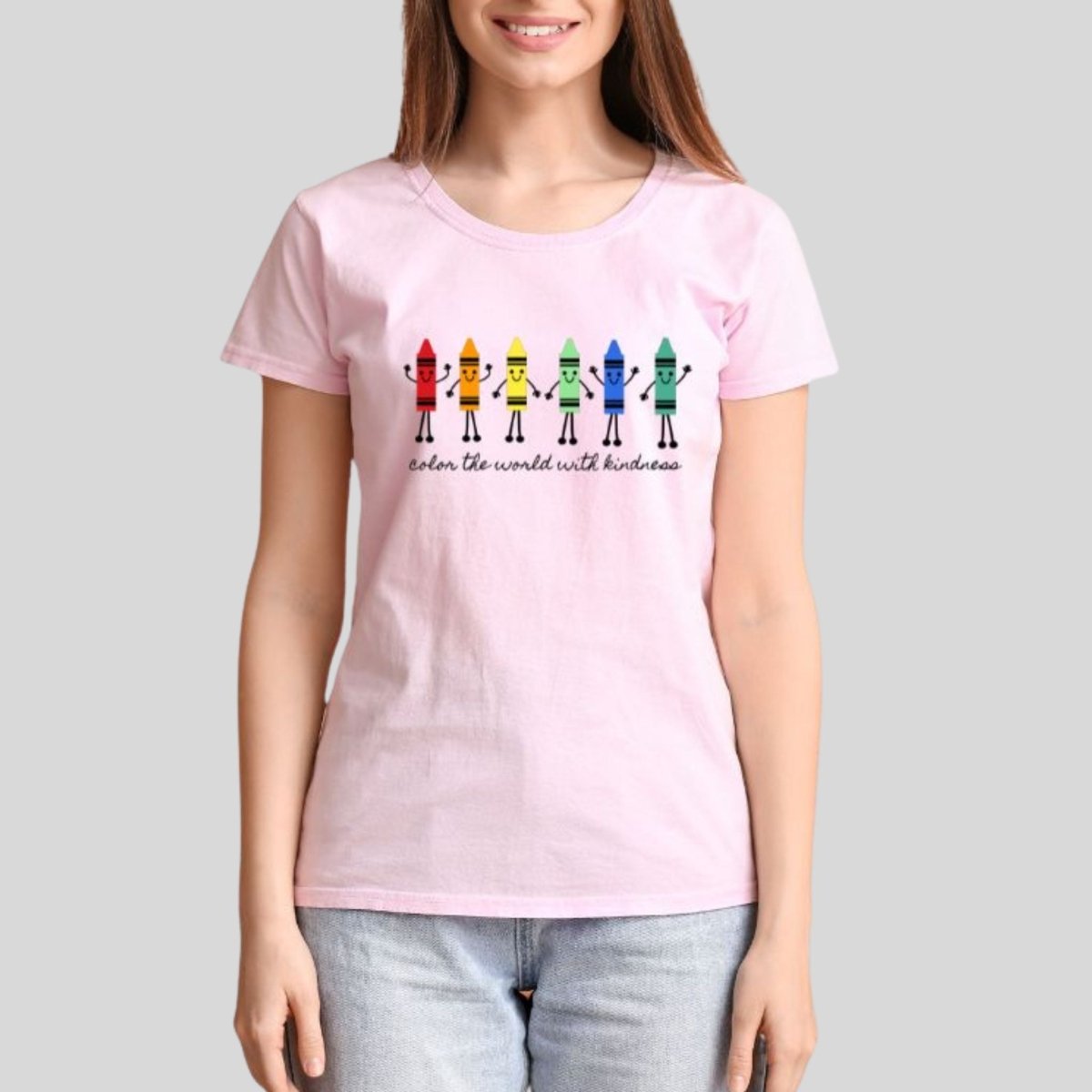 woman wearing a pink tshirt with Color the World with Kindness Crayons Teacher graphic on front. Colored crayons with faces and hands and black lettering under them.- Little Gift Nook