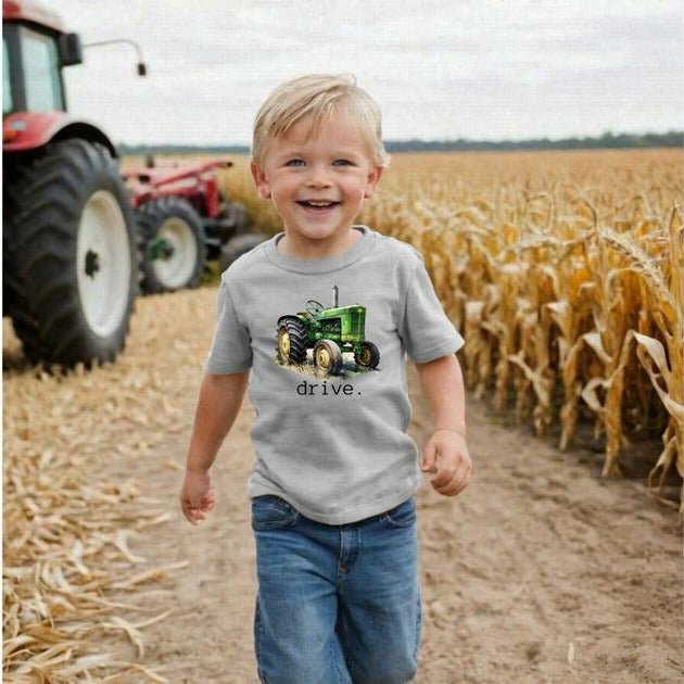 Tractor Drive Toddler Tshirt. Little boy wearing this light gray tee with green tractor on front and drive in black lettering underneath. Great gift idea. - Little Gift Nook.