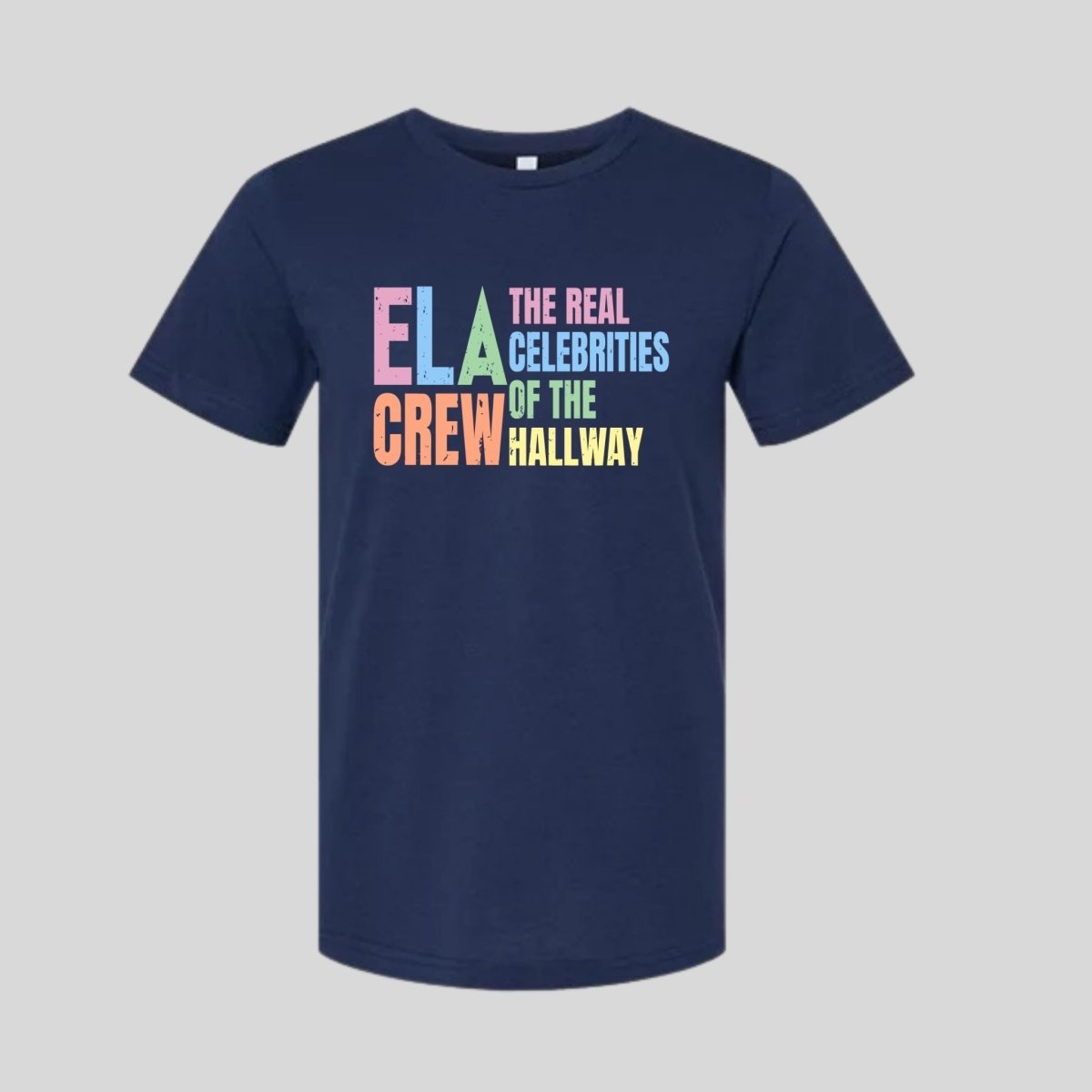 Navy tshirt with pastel retro vibe text "ELA CREW The Real Celebrities of the Hallway" laying flat on a gray background. Little Gift Nook