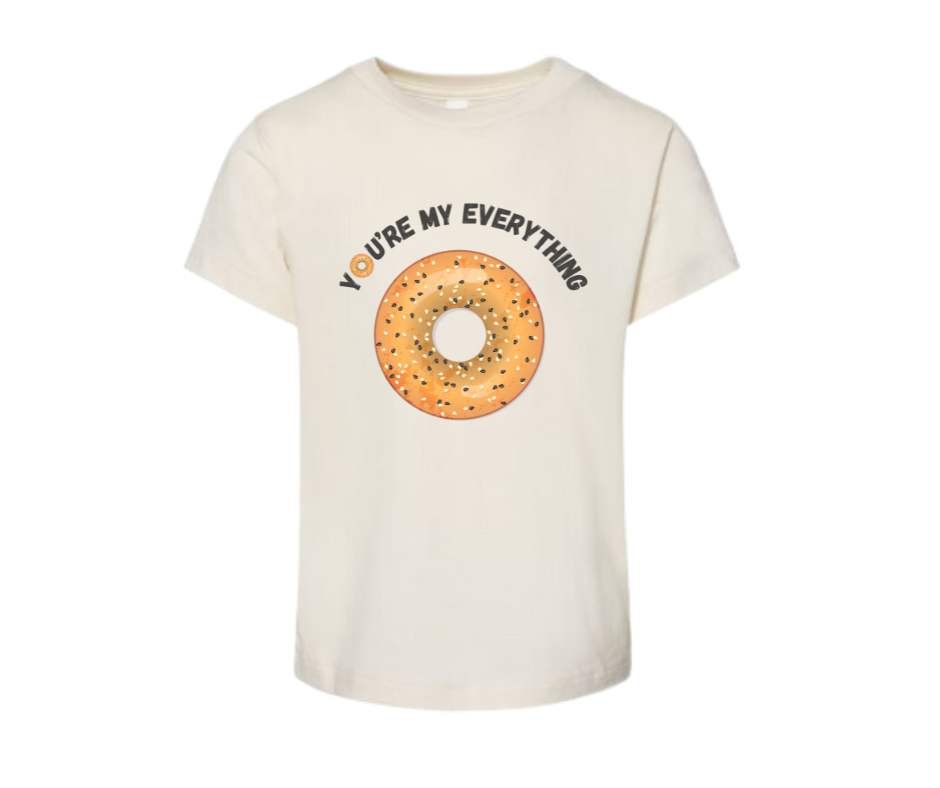beige tshirt with image of seeded bagel with text "YOU'RE MY EVERYTHING" on white background.