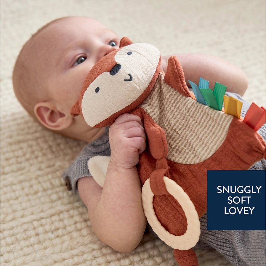 baby holding orange fox sensory teether toy.