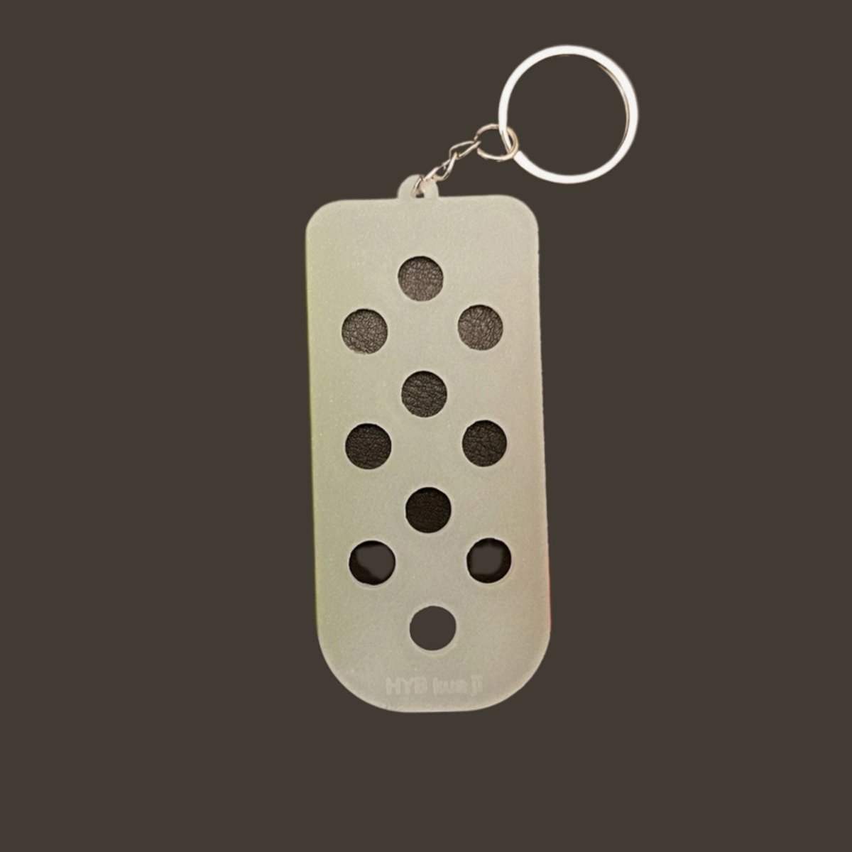 Shoe charm keychain clear plastic glows in the dark on metal keyring on gray background.