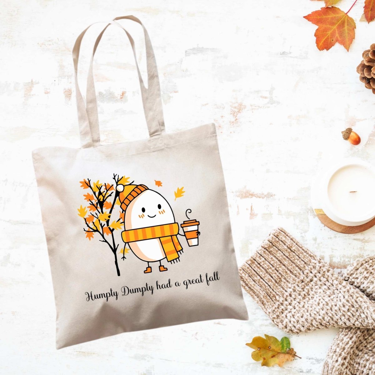 creme canvas tote bag with orange yellow fall leaves tree, humpty dumpty egg in hat and scarf holding a latte. Says "Humpty Dumpty had a great fall" in black text under image. Little Gift Nook