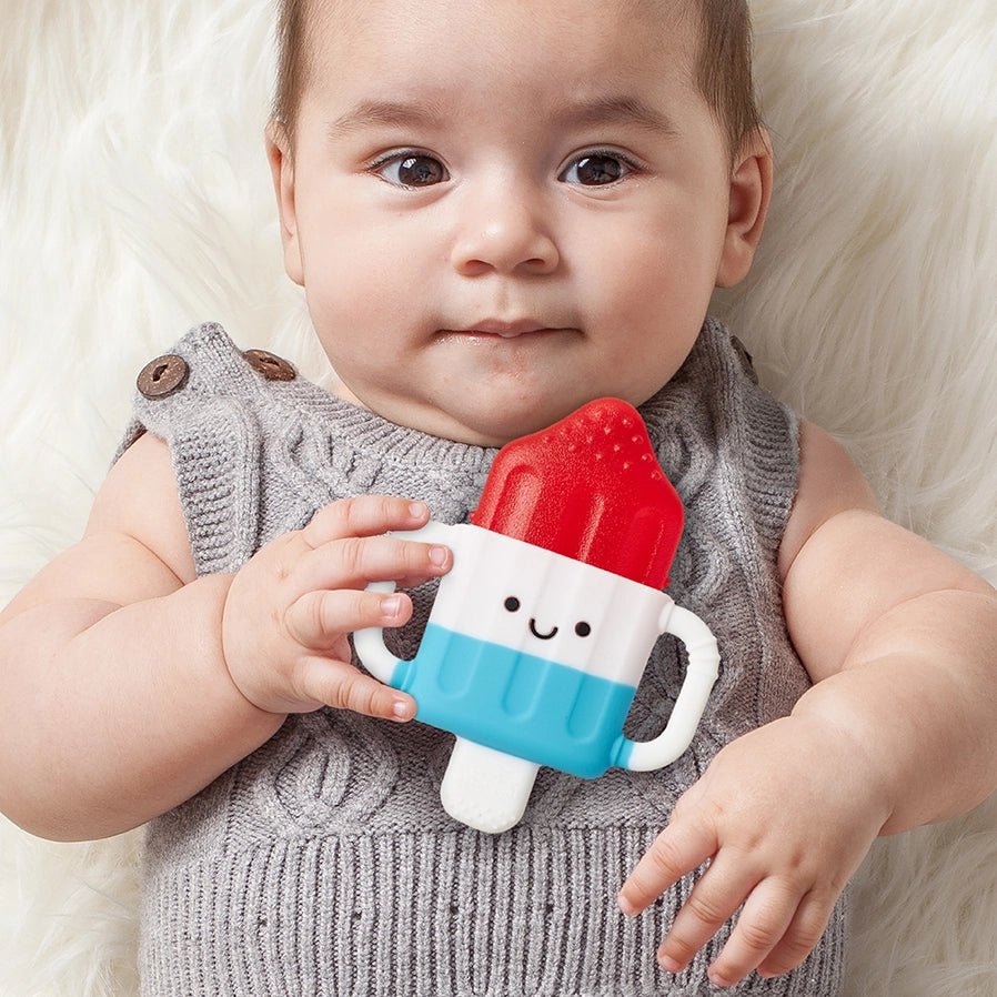 Itzy Cool Cold Baby Teether Hero Pop red white and blue teether in baby's hand - water filled top and no chill handles - Little Gift Nook