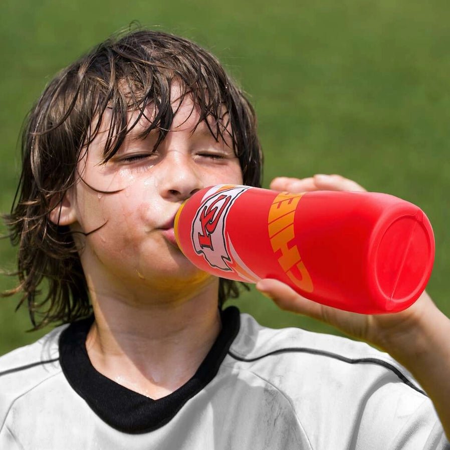 Kid drinking from Kansas City Chiefs logo 32oz BPA Free squeezy water Bottle in football uniform on field.