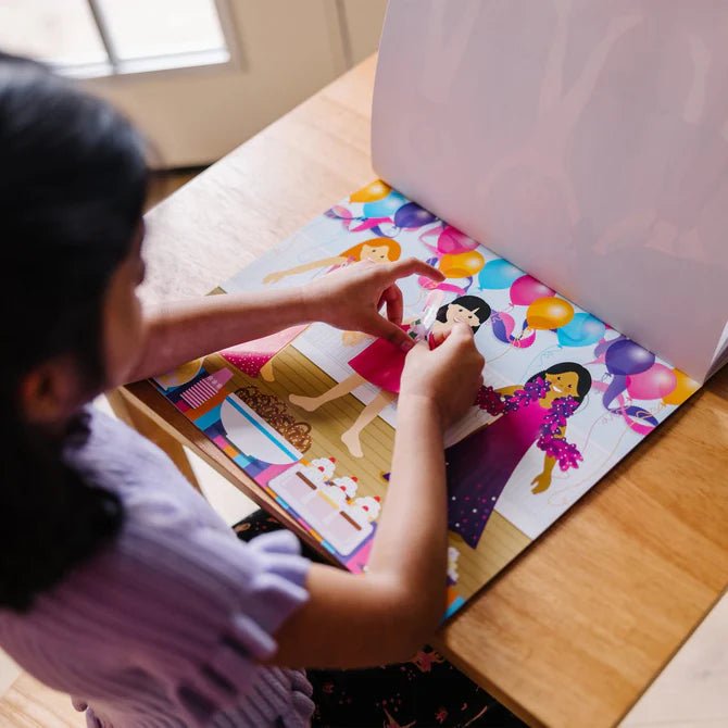 Little girl playing with Melissa & Doug reusable sticker pad on desk.