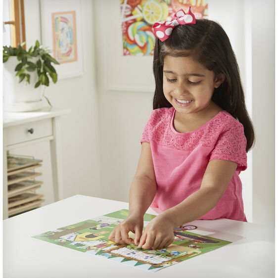 Little girl playing with Melissa & Doug reusable sticker pad Play house on a table.