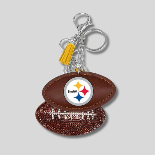 Keychain shaped like a football with Steelers logo and rhinestones on other side on a gray background. Little Gift Nook