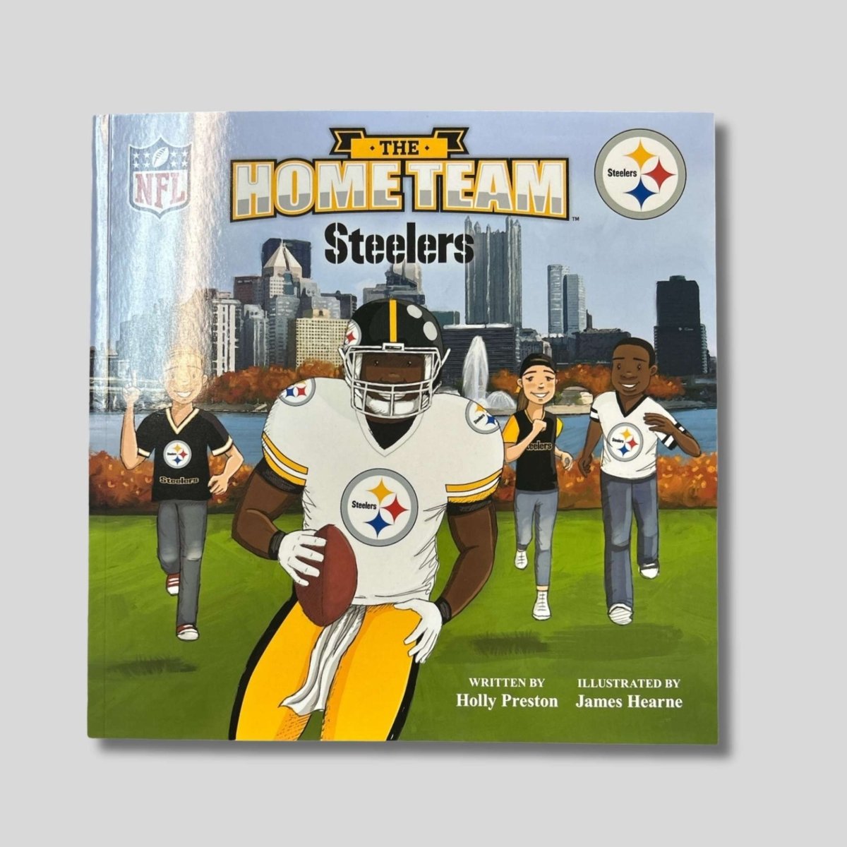 Book cover of 'The Home Team Steelers' with a football player and cityscape background.