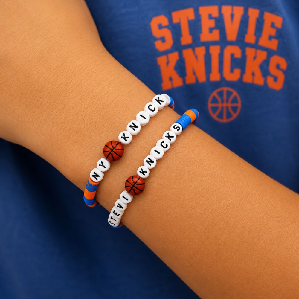 Woman's wrist wearing blue and orange NY Basketball "Stevie Knicks" friendship bracelets against a blue tshirt.