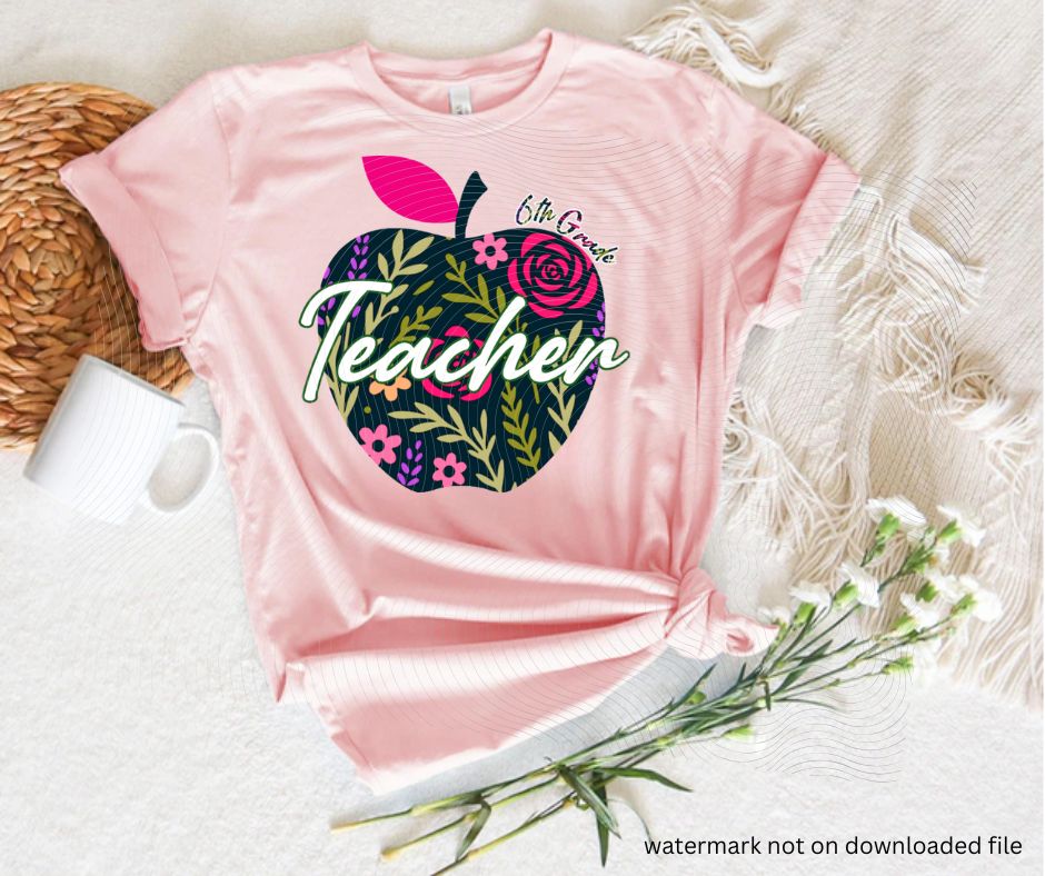 Pink tshirt with navy floral apple 6th grade teacher image on front laying flat on white background with flowers.