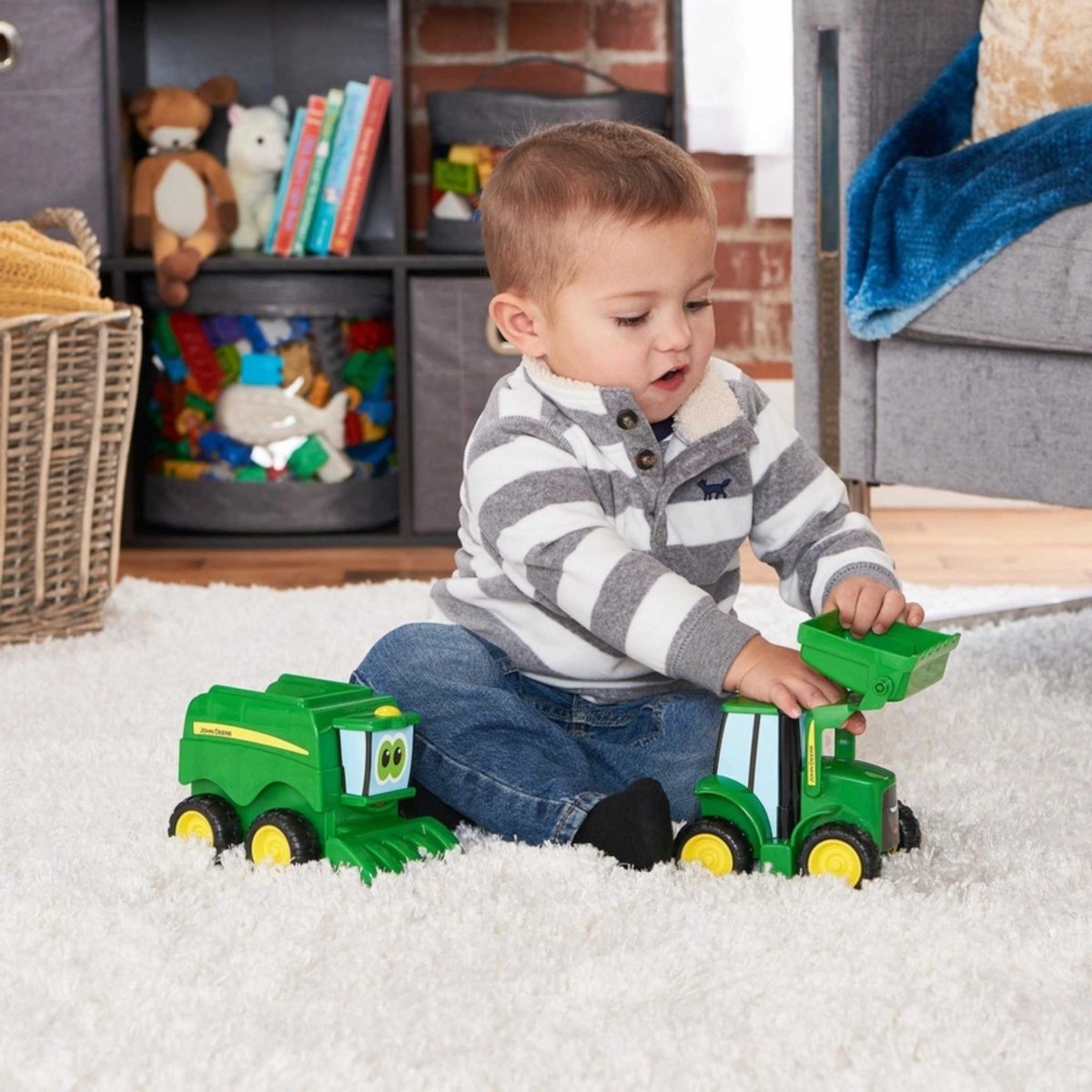 Little boy playing with John Deere 2 piece toy tractor set scoop and haul on white carpet.