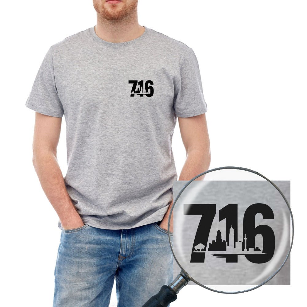 Person wearing a gray t-shirt with '716' and skyline and buffalo printed on left chest, magnifying glass showing a detailed version of the design.