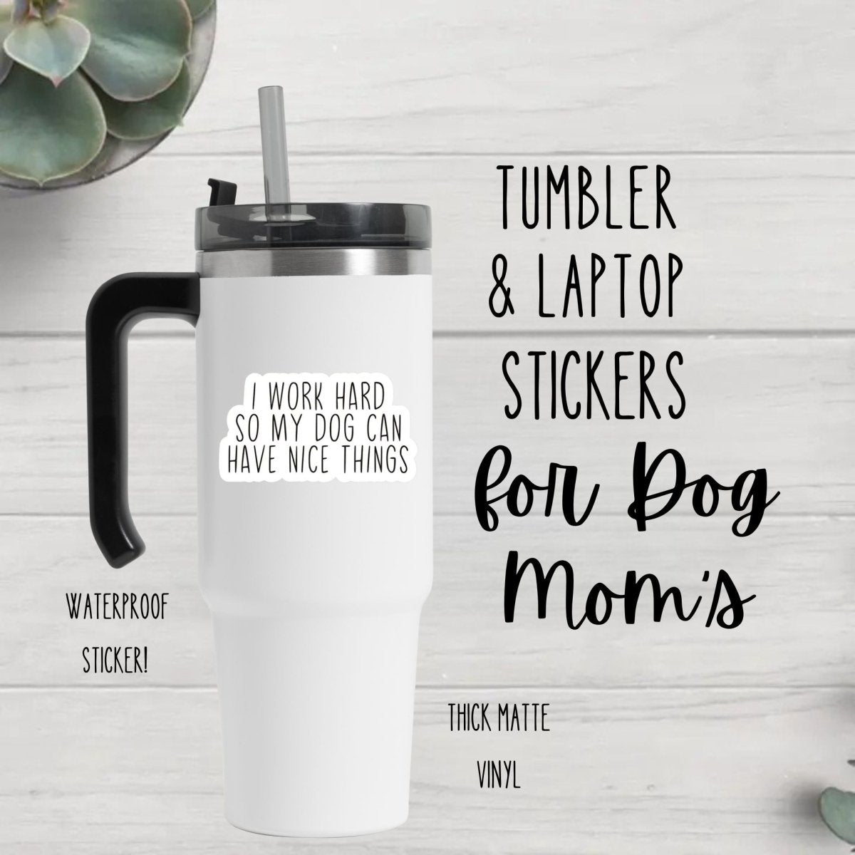 white tumbler with white black text sticker "I Work Hard so my Dog can have nice things" on front sitting on wood background.