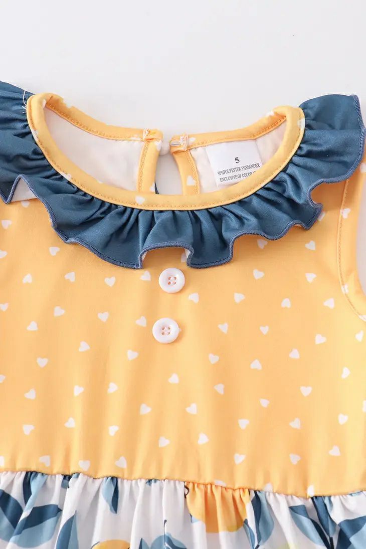 Citrus & Sunshine Lemons Ruffle Twirl Dresses. Close up of bodice of dress. Yellow with white heart print and navy ruffle neckline. 2 white buttons on front. Little Gift Nook.