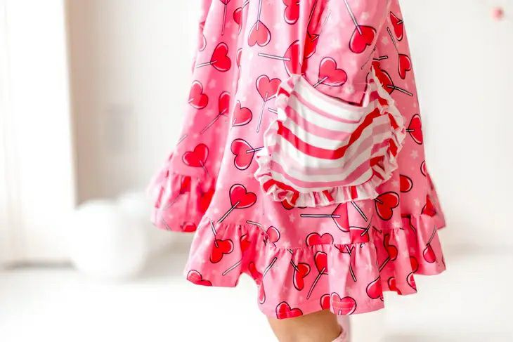 Sucker for Love Hearts Ruffle Twirl Dress. Pink heart sucker print dress with striped ruffle pockets close up. - Little Gift Nook