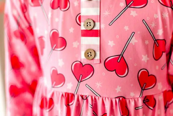 Sucker for Love Hearts Ruffle Twirl Dress. Close up of heart sucker print and 3 accent buttons at chest. - Little Gift Nook