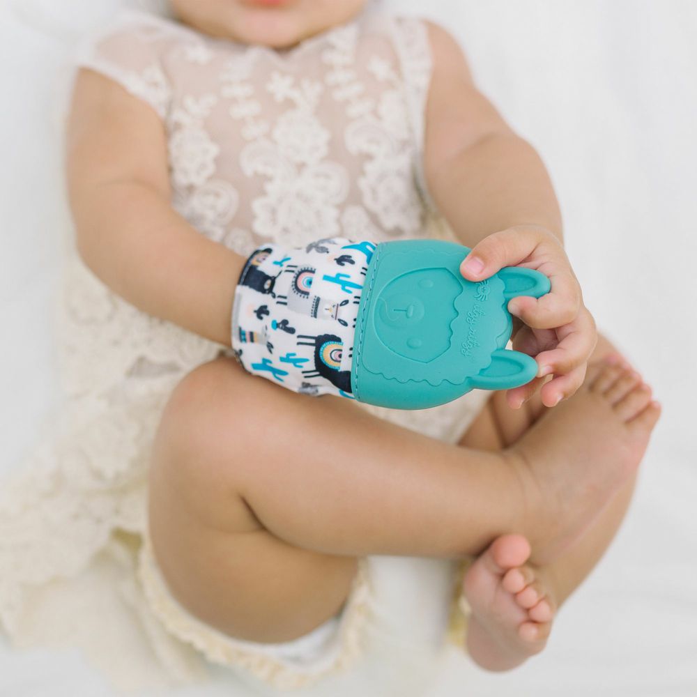 baby holding Itzy Ritzy teal llama teething mitt.