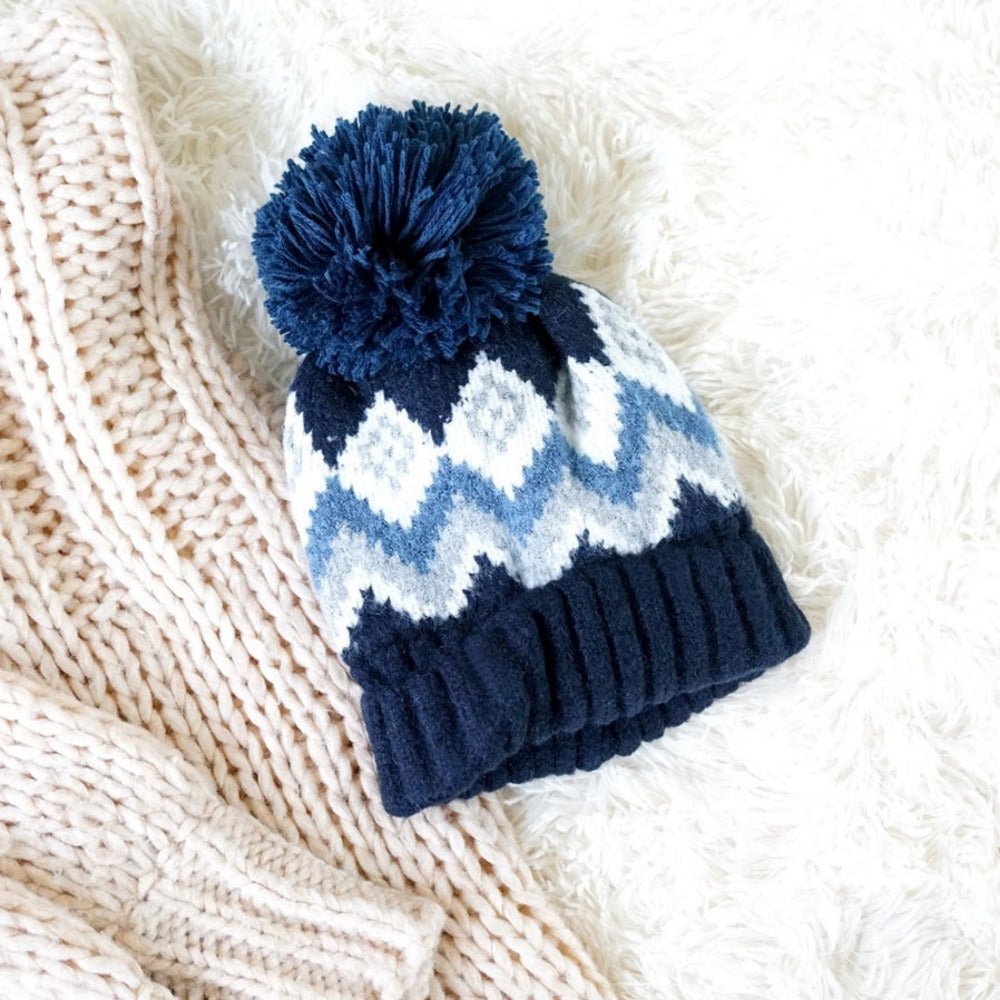 Aztec knit lined pom hat on white fur background.