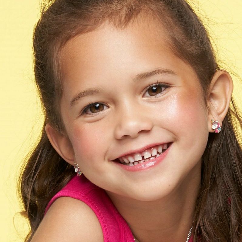 Little girl wearing pink blue gold stud unicorn earrings.