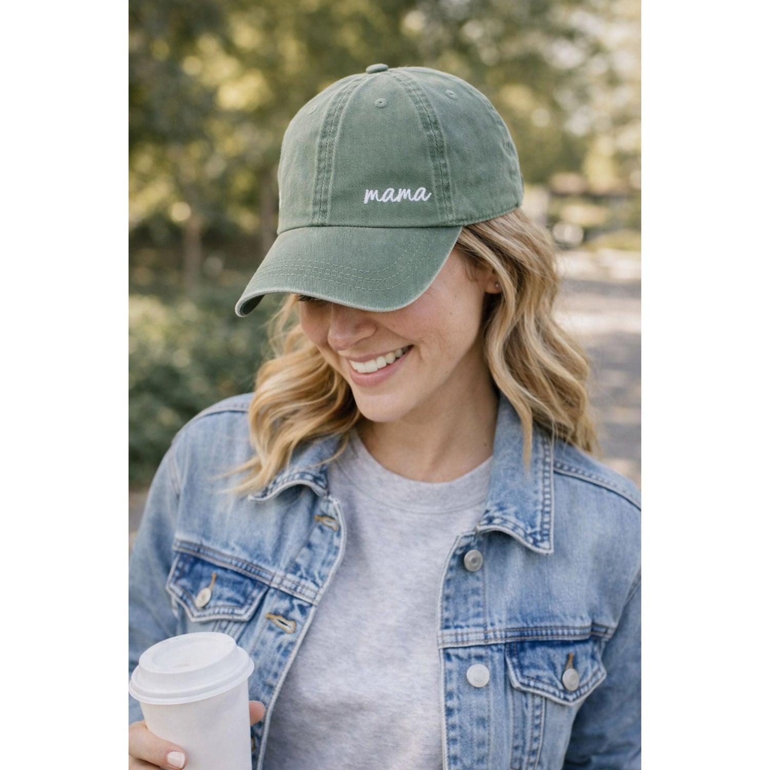 woman in sage green mama embroidered hat with coffee outdoors.