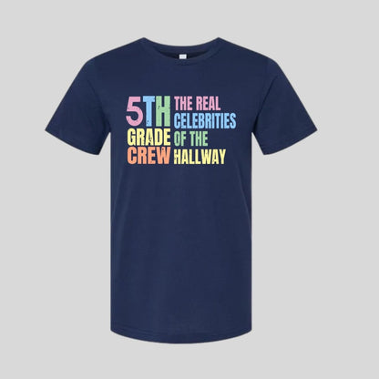 Navy blue t-shirt with colorful text "5th Grade Crew The Real Celebrities of the Hallway" tshirt on gray background. Little Gift Nook