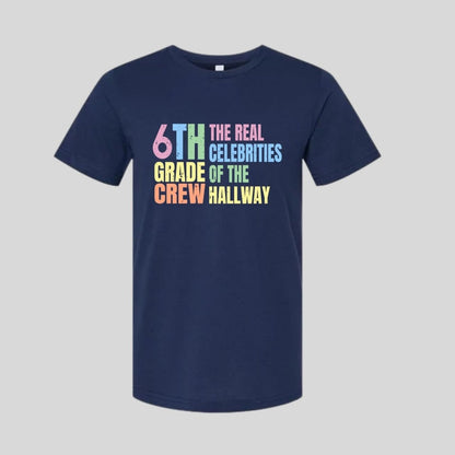 Navy blue t-shirt with colorful text "6th Grade Crew The Real Celebrities of the Hallway" tshirt on gray background. Little Gift Nook