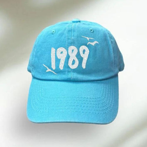 Blue Taylor Inspired 1989 Baseball Hat. Fits adults and older kids.  Adjustable in back.  White glitter number 1989 with birds on front. Little Gift Nook.