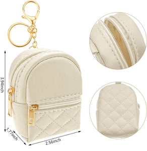 Cream quilted mini backpack keychain with 2 pockets that open with gold zippers and gold ring, chain, and lobster clip. Measures 3.94 inches tall.  Little Gift Nook.