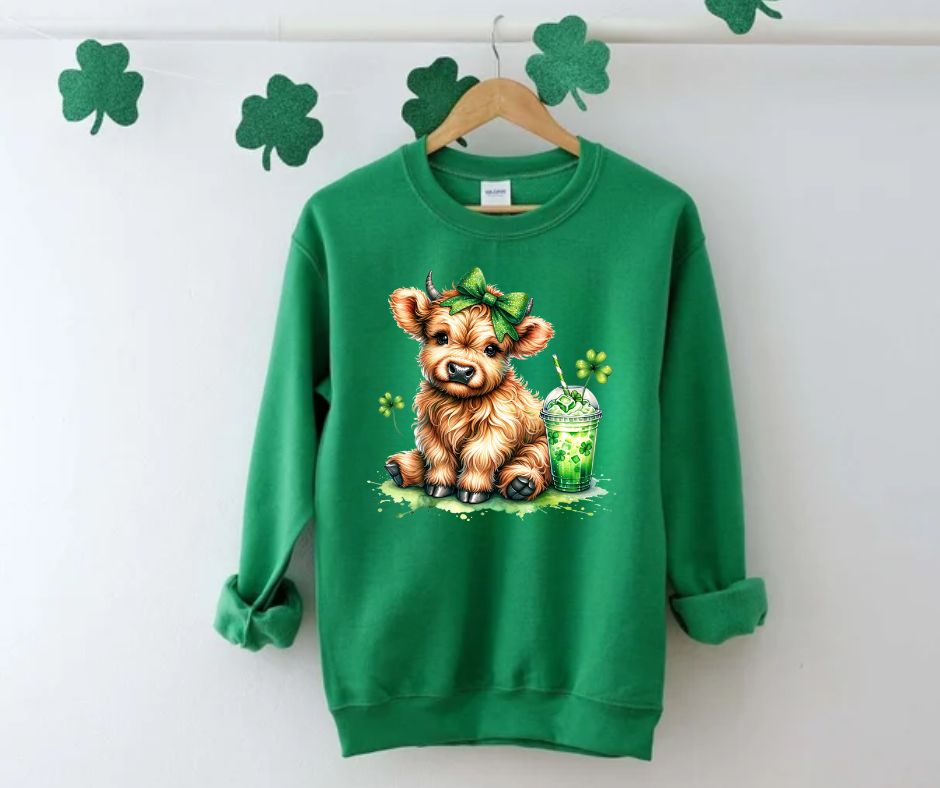 Lucky Highland Cow St. Patty's Crewnecks & Tshirts. Irish Green Fleece lined crewneck  with adorable Highland cow, clovers, green bow, and shamrock drink.  Utterly Cute!  Little Gift Nook.