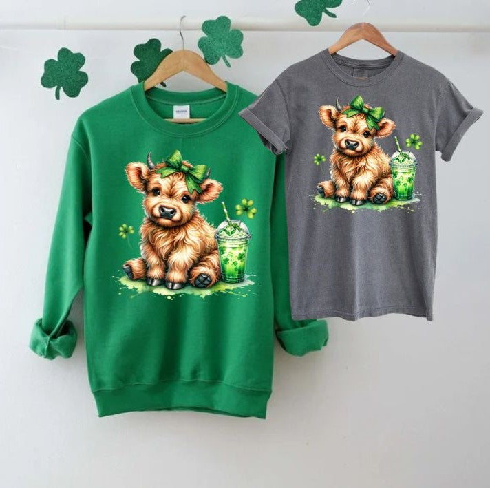 Lucky Highland Cow St. Patty's Crewnecks & Tshirts. Irish Green Fleece lined crewneck or Pepper Gray Short sleeved Tshirt with adorable Highland cow, clovers, green bow, and shamrock drink.  Utterly Cute!  Little Gift Nook.