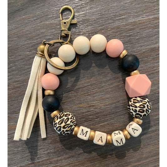 Silicone Beaded Wristlet Mama Keychain. Cream, light pink, black, and animal cheetah print silicone beads with gold painted beads. Cream cubed white beads with MAMA on all sides. Metal keyring and clip, cream tassel. - Little Gift Nook.