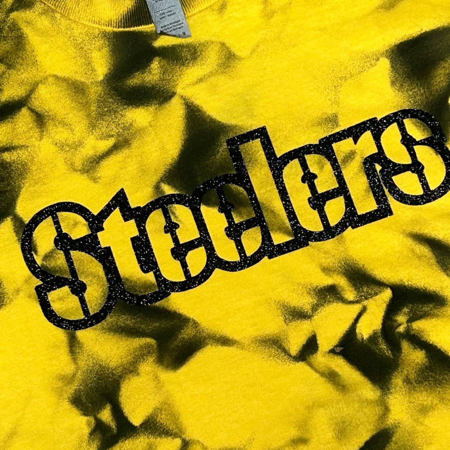 Steelers Black Yellow Dyed Glitter Letter Tshirt. Close up of tie dye shirt with glitter black lettering.- Little Gift Nook