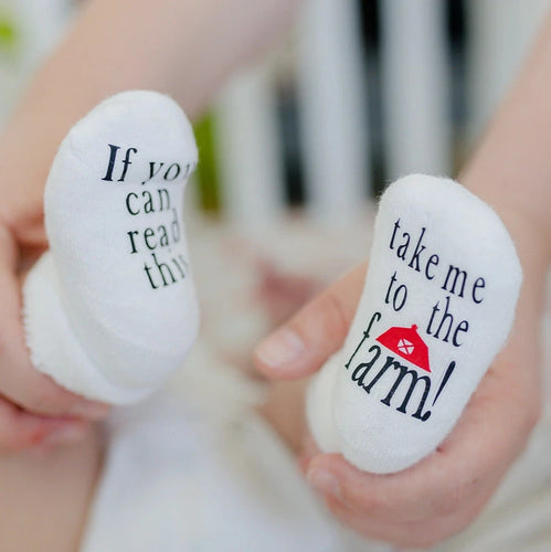 Take Me To the Farm Baby Socks. White baby socks with black lettering & red barn on bottoms.