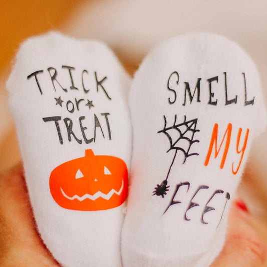 Trick or Treat Smell My Feet Baby Socks. White baby socks with bottoms of socks have pumpkin and spider image with lettering. - Little Gift Nook