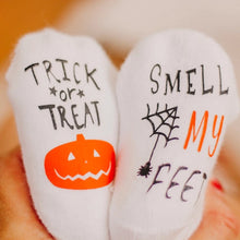 Load image into Gallery viewer, Trick or Treat Smell My Feet Baby Socks. White socks with black &amp; orange lettering, spiderweb, and pumpkin on bottoms.