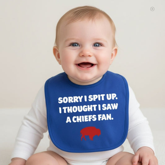 Baby wearing blue bib with red buffalo "sorry I spit up. I thought I saw a Chiefs fan." in white text on front. Baby sitting on light gray background. Little Gift Nook