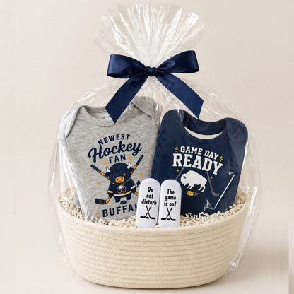 Gray and navy buffalo hockey theme 3 piece baby gift set onesie, bib, and socks in a creme rope basket with navy bow on a beige background.