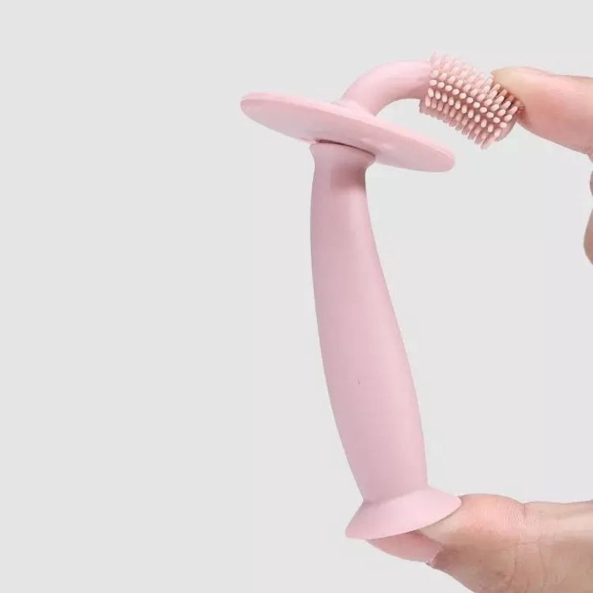 ToothieBrush Baby & Toddler Toothbrush soft, bendable show in pink with hand bending it on a white background. 