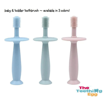 The Teething egg baby tooth brushes in blue green or pink standing on white background with logo.