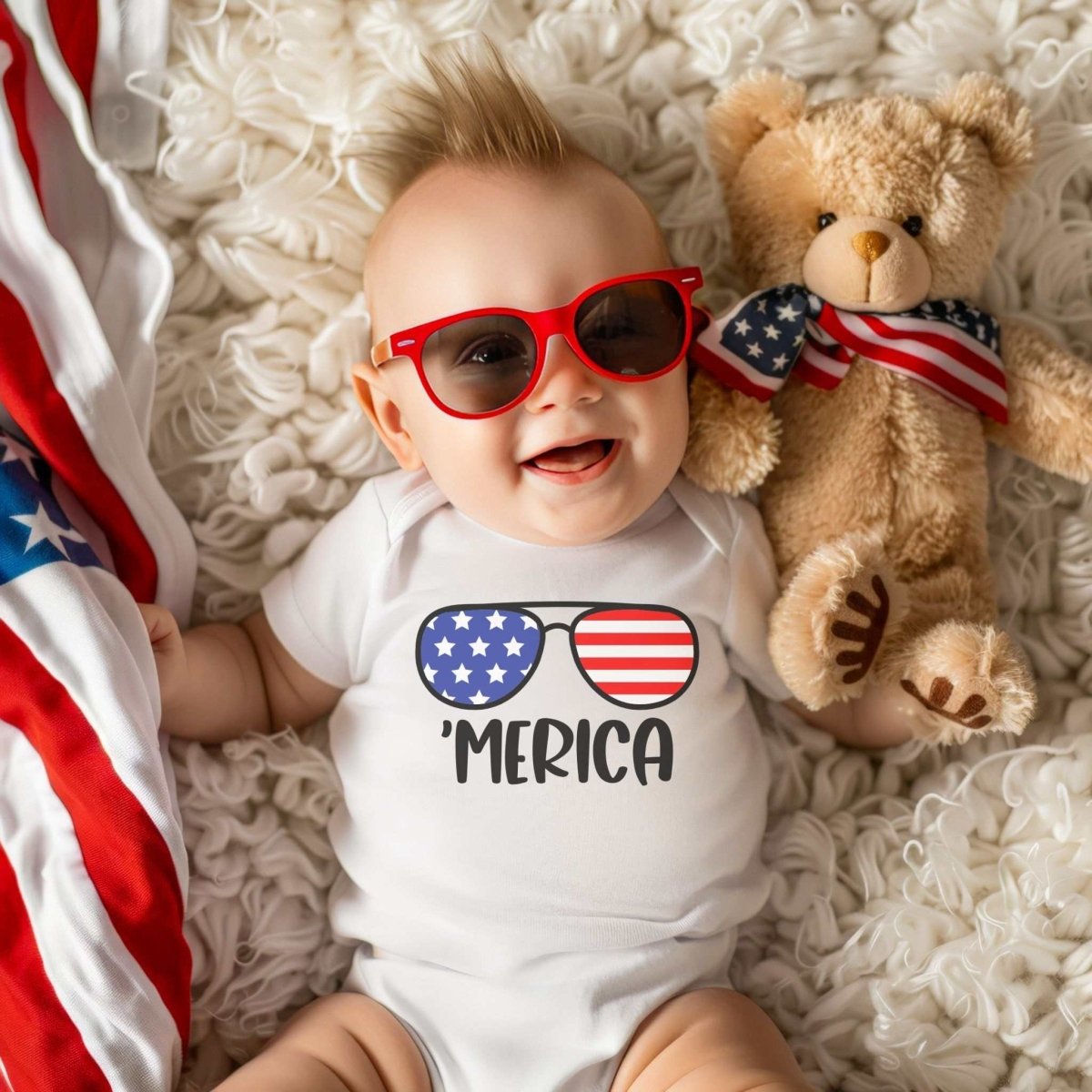Baby laying on soft white blanket with American Flag and teddy bear wearing white onesie with red blut stars and stripes image of sunglasses and 'MERICA on front - Little Gift Nook
