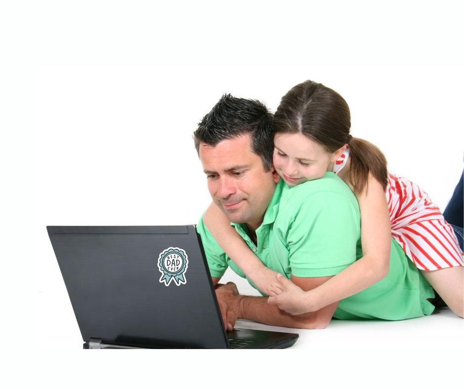 dad and daughter sitting in front of a laptop and blue ribbon image sticker with "Best DAD ever" on front of laptop. Image on white background.